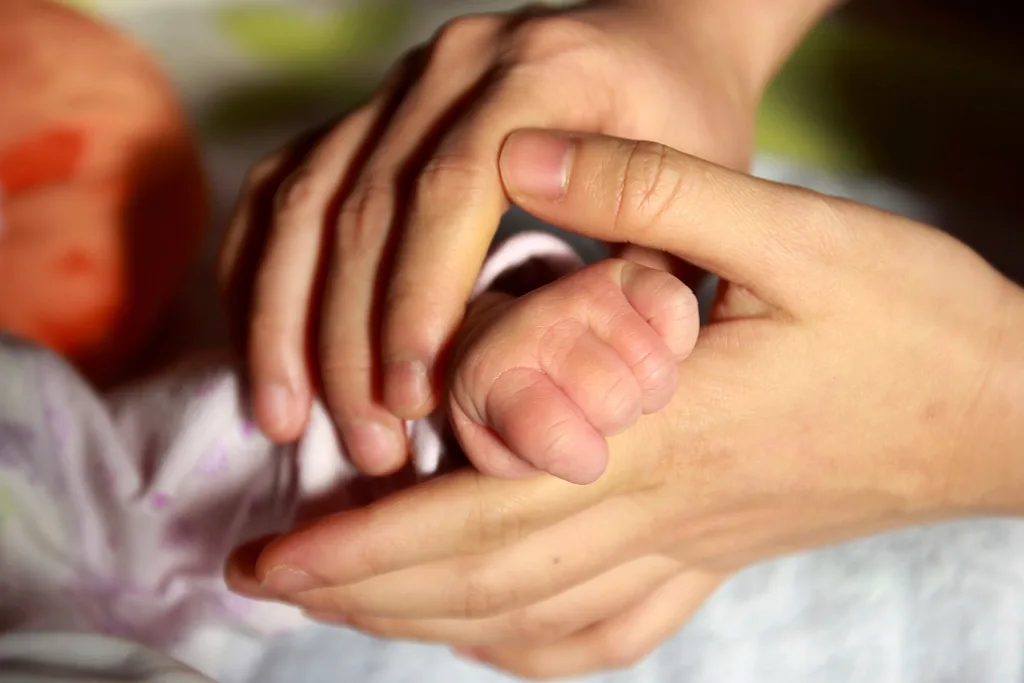 A parent holding a newborn baby’s hand