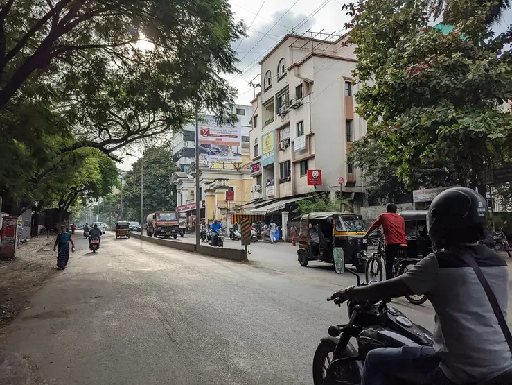 A street in Pune with shops, rickshaws and two-wheelers