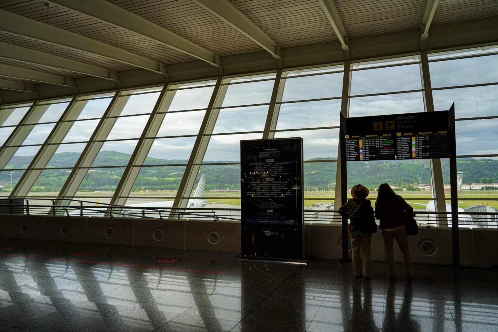 Two travellers checking an airport arrivals board