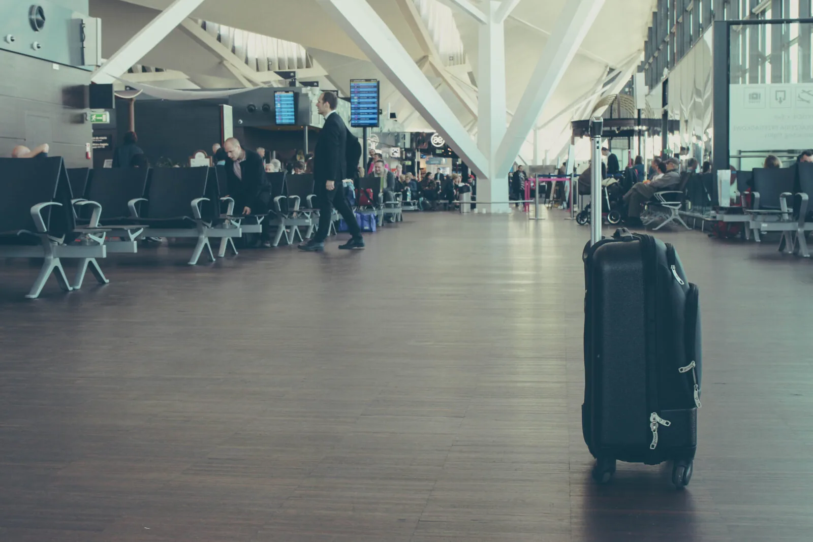 Traveller with cabin baggage waiting in an airport departure lounge