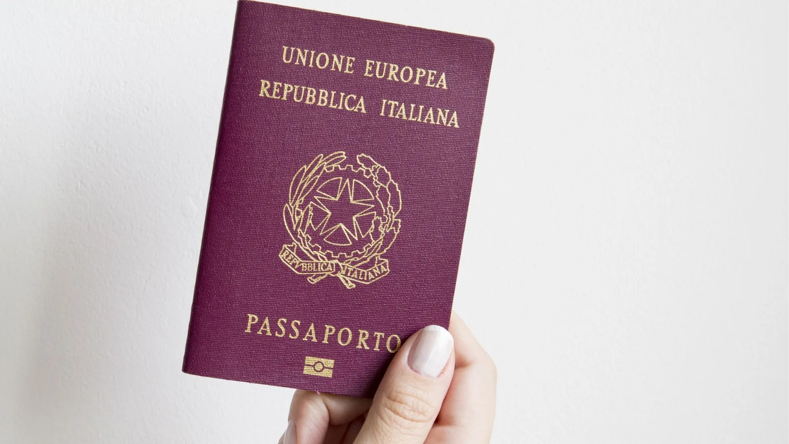 A passport held up against a plain wall