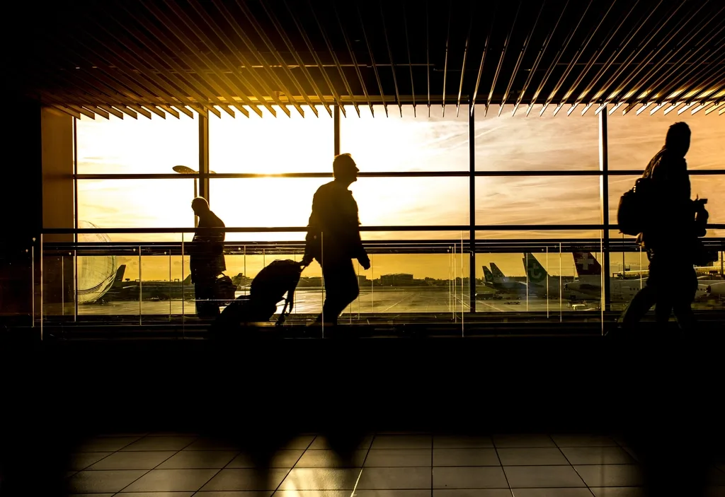 Travellers walking through an airport departure hall at sunset